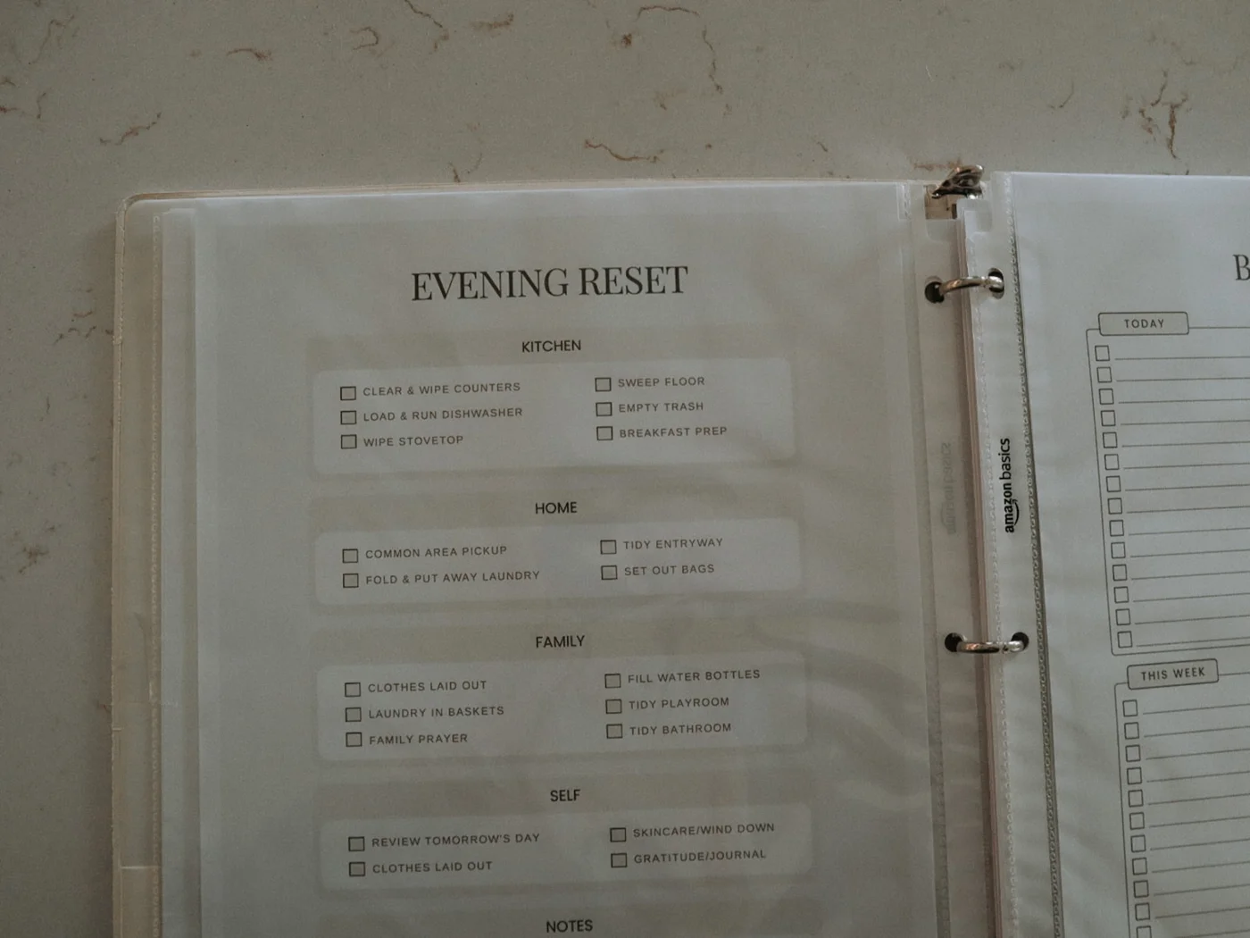 An open home management binder showing an Evening Reset page and task list