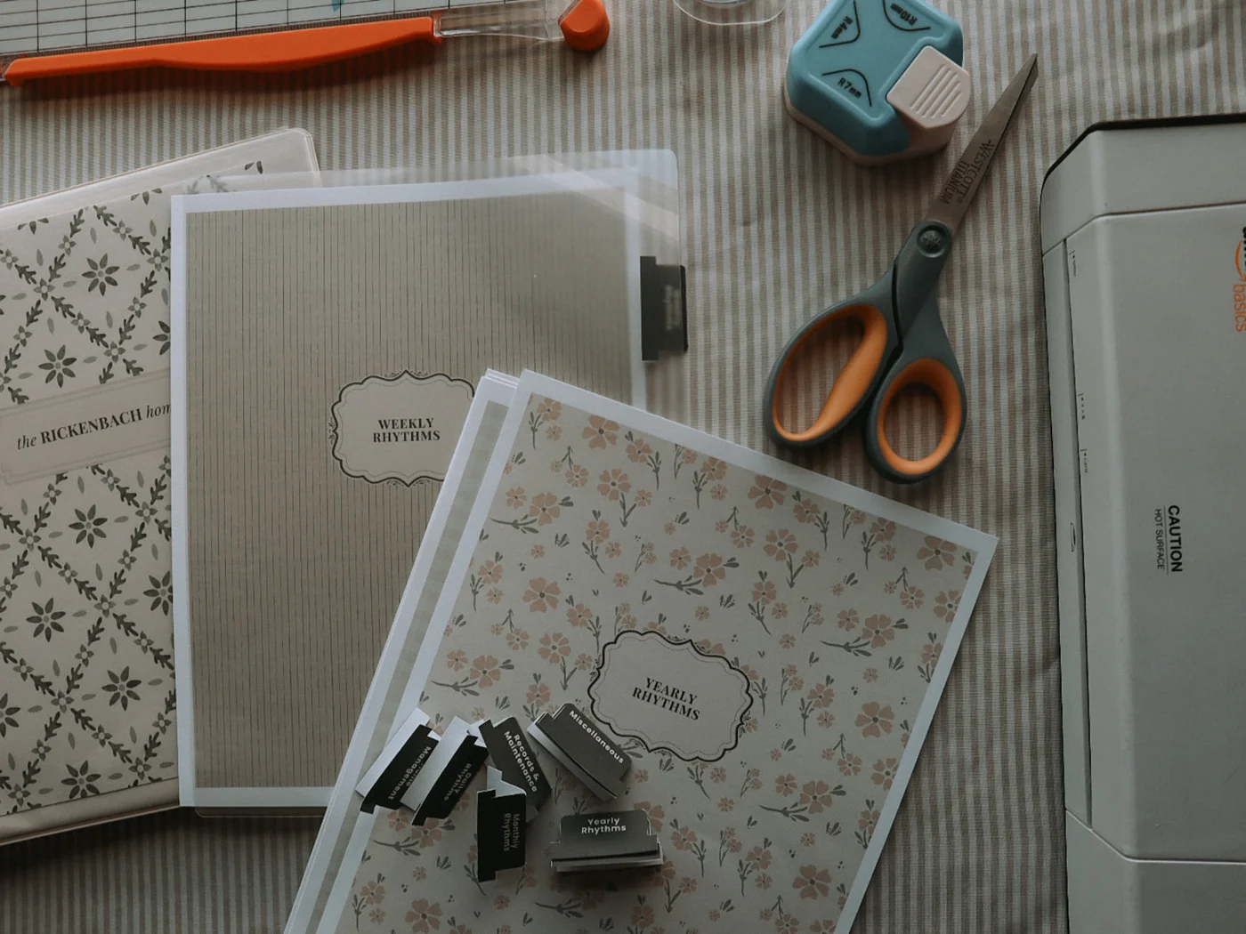 Printed home rhythm dividers beside scissors, tabs, and a laminator